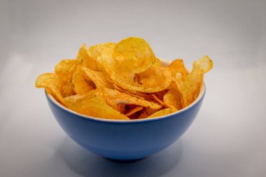 Çıtır çıtır ve baharatlı cipslerle dolu mavi bir kase.