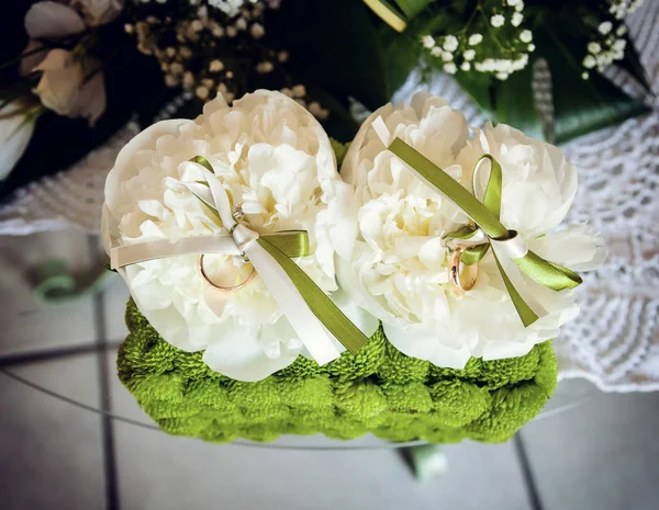 Witte pioenrozen en groene bloemen met twee gouden ringen. — Stockfoto