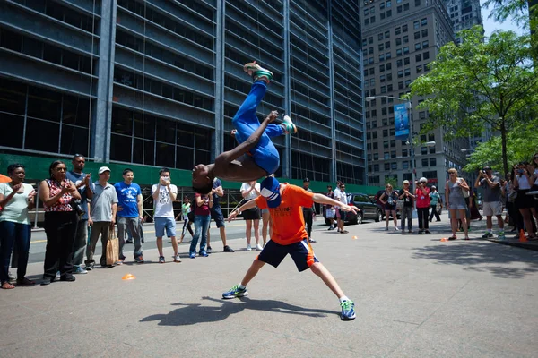 A black man doing a somersault over a tourist in Lower Manhattan — Stock Photo, Image