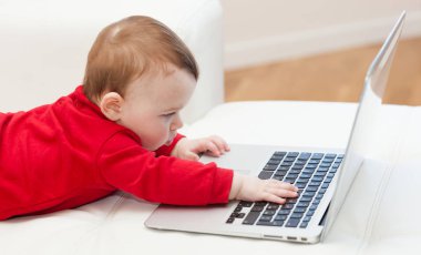 Bir dizüstü bilgisayar kullanan bebek kız