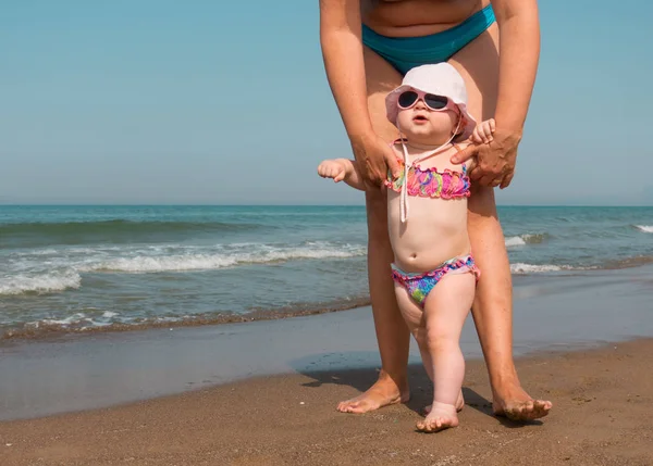 Madre ayudando a su bebé a pararse y caminar en la playa — Foto de Stock