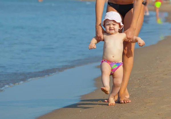 Mamá enseña a su hija a caminar a la playa . — Foto de Stock