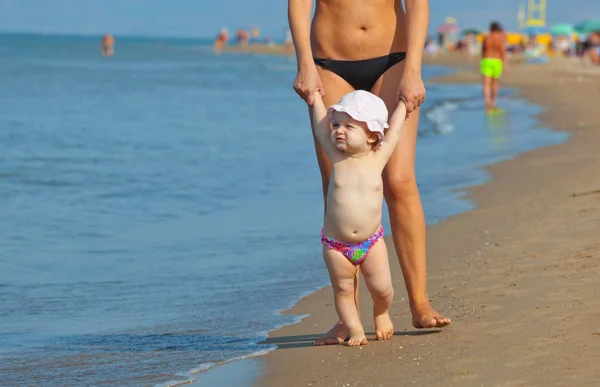 Mamá enseña a su hija a caminar a la playa . — Foto de Stock