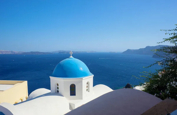 Blauwe koepel van kerk en blauwe zeewater in Santorini. — Stockfoto
