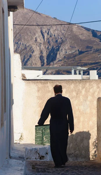 Sacerdote ortodoxo grego caminhando na pitoresca aldeia de Pyrgos . — Fotografia de Stock