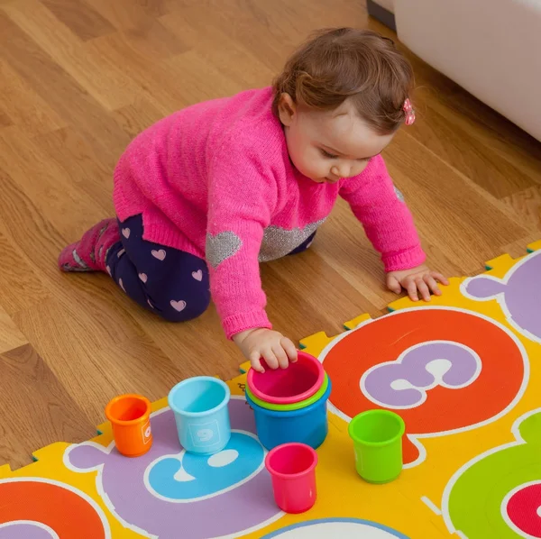 Bebé niño juega con tazas de colores — Foto de Stock