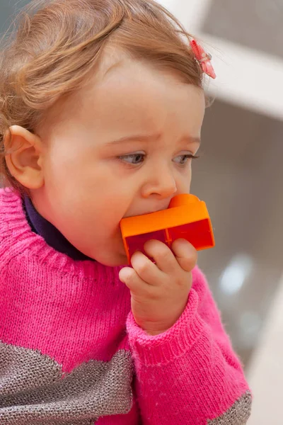 Batole dítě pustí v její ústa gumové stavební bloky. — Stock fotografie