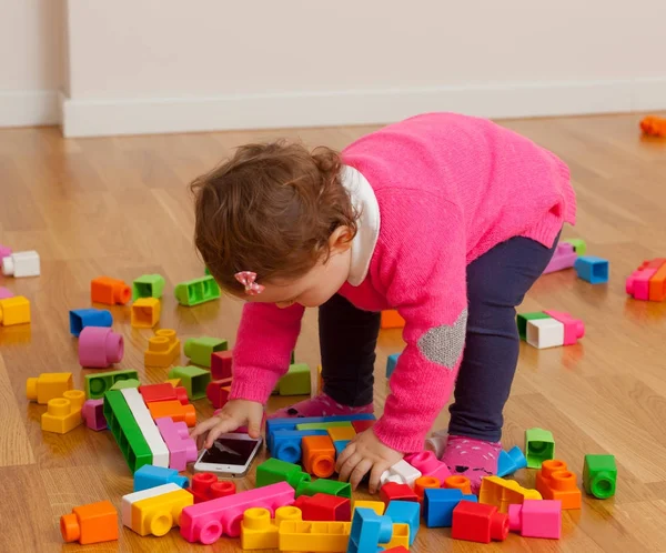 Criança Bebê Menina Brinca Com Telefone Inteligente Entre Blocos Construção — Fotografia de Stock