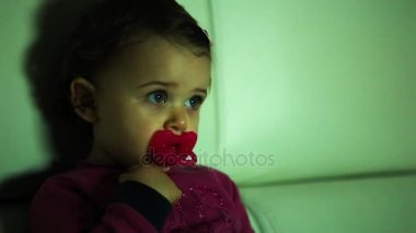 Küçük bebek kız portresi ekran karanlıkta seyreder.
