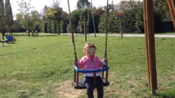 Niña en un columpio en un parque — Vídeos de Stock