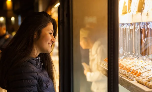 Mujer joven mirando el escaparate de una joyería al aire libre — Foto de Stock