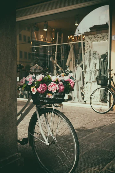 Bicicleta com flores na cesta deitada ao lado da parede . — Fotografia de Stock