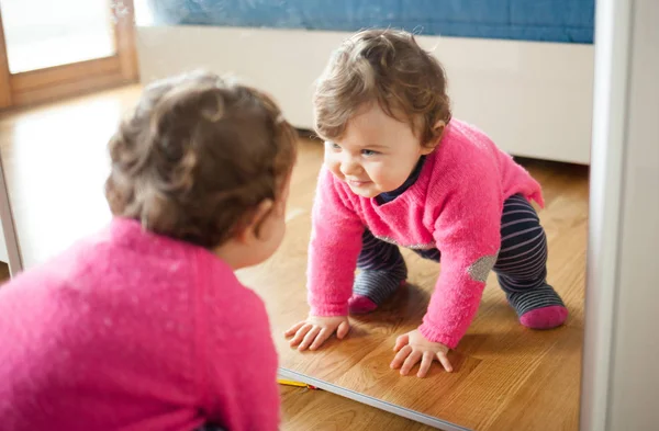 Niña jugando con espejo en el dormitorio — Foto de Stock