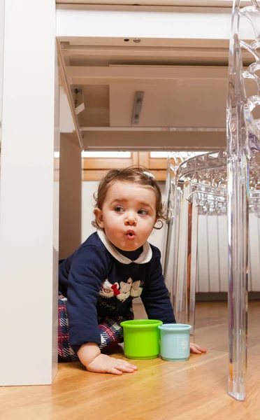 Toddler baby girl playing under the table — Stock Photo, Image