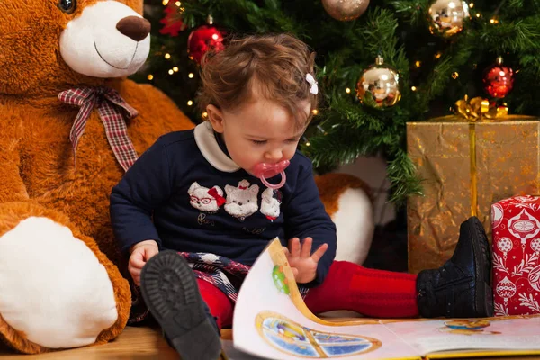 Kleinkind liest Märchen in der Nähe des Weihnachtsbaums. — Stockfoto