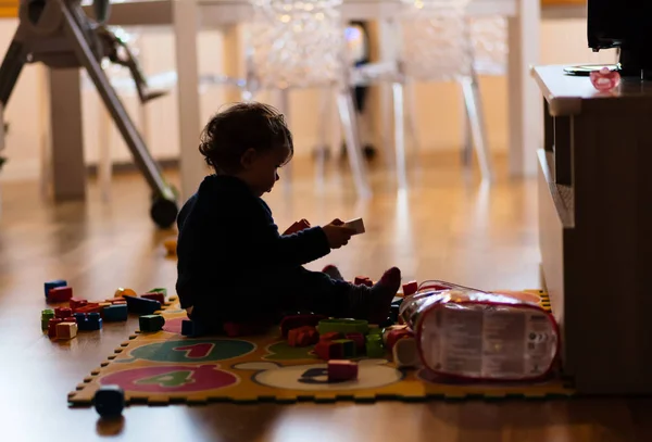 Ailhouette de niño pequeño pagando con juguetes en casa . — Foto de Stock