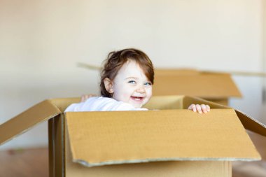 Kahverengi karton kutu içinde oturan toddler bebek kız.
