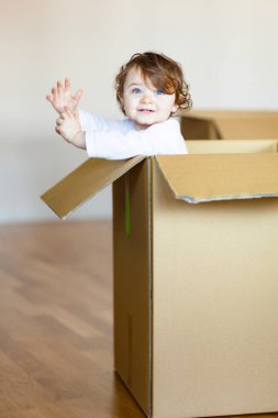 Kahverengi karton kutu içinde oturan toddler bebek kız.