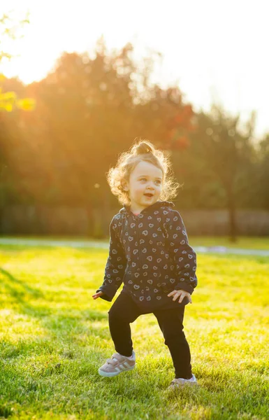 Babymeisje speelt in het park in tegenlicht. — Stockfoto