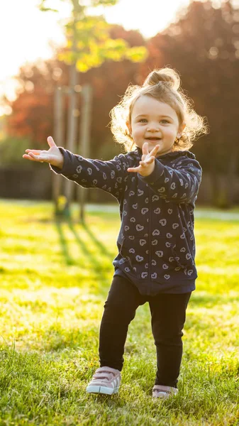 Niña pequeña juega en el parque en contraluz . —  Fotos de Stock