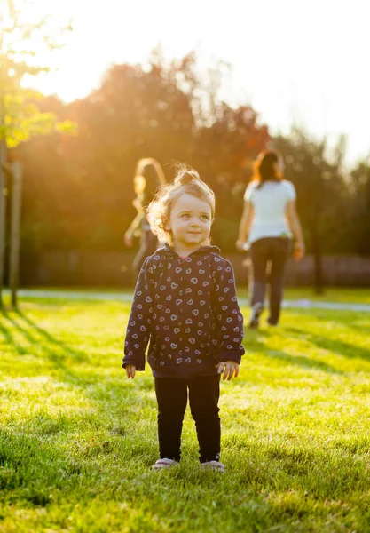 Kis baba lány játszik a parkban, a háttérvilágítás. — Stock Fotó