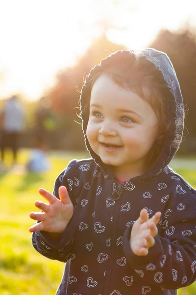 Babymeisje speelt in het park in tegenlicht. — Stockfoto