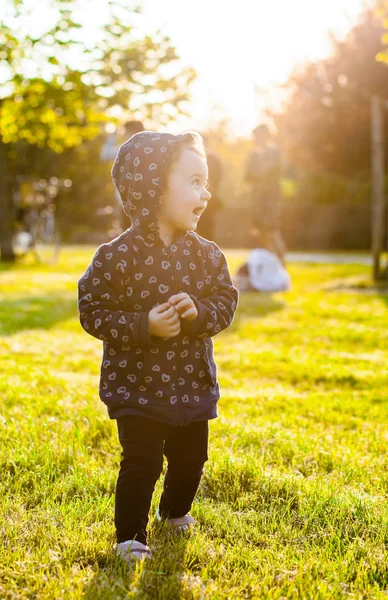 小さな女の赤ちゃんはバックライトで公園で遊ぶ. — ストック写真