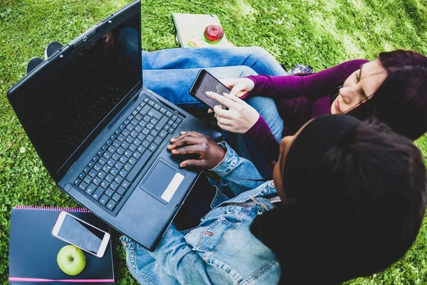 Multiracial couple of women using laptop and cell phone at the p — ストック写真