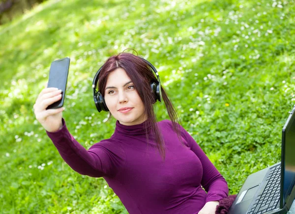 Junge Studentin im Park hört Musik mit Kopfhörern — Stockfoto