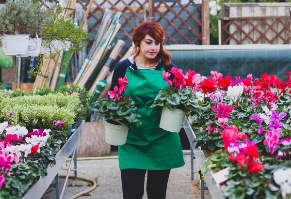 Jovem florista com cabelo vermelho trabalha em um berçário . — Fotografia de Stock