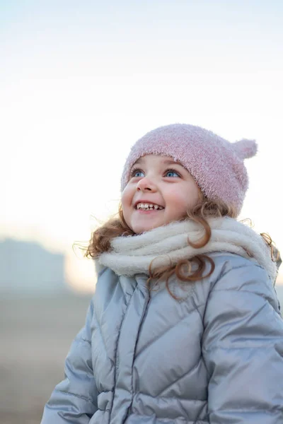 Adorable little girl smiles and looks at the sky. — Stockfoto