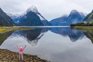 Genç Asyalı gezgin Milford Sound, Fiordland Ulusal Parkı, Güney Adası, Yeni Zelanda 'da başarıyı kutluyor
