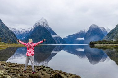 Genç Asyalı gezgin Milford Sound, Fiordland Ulusal Parkı, Güney Adası, Yeni Zelanda 'da başarıyı kutluyor