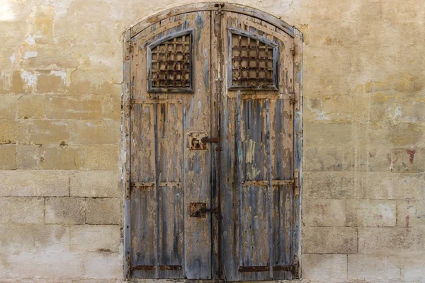 Vintage old warehouse brown door with ancient limestone brick wall