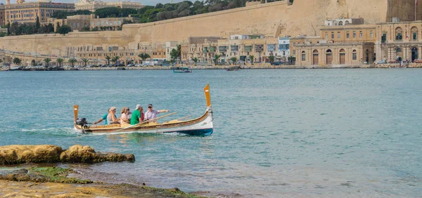Tradicional góndola maltesa dghajsa con los turistas en el Gran Puerto con vistas panorámicas de La Valeta —  Fotos de Stock