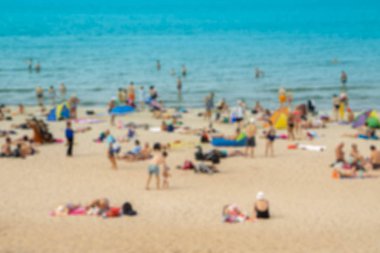 Bulanık odaklı görünüm. Denize ya da okyanusa yakın plajdaki insanlar