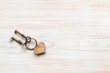 Arka planda iki bronz renkli anahtar ve kalp klasiği beyaz boyanmış tahtalar var. Mesaj için yer. Üst görünüm.