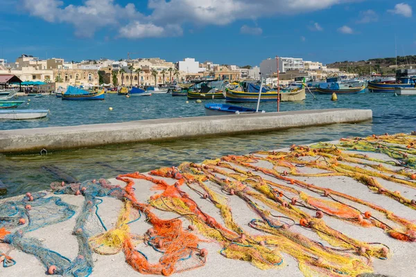 Redes de pesca maltesas coloridas tradicionales en el muelle de hormigón en Marshallock o Marsaxlokk, pueblo de pescadores en Malta —  Fotos de Stock