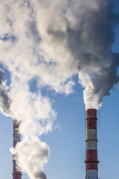 Industrial smokestacks with thick smoke clouds over blue sky. Global warming. Air pollution.