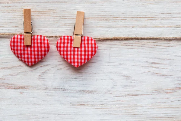 Valentijnsdag achtergrond met een paar rode harten op wasknijpers aan houten rand. Valentijnsdag concept — Stockfoto