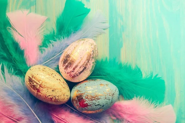 Vue de dessus des œufs de Pâques colorés et des plumes sur fond en bois — Photo