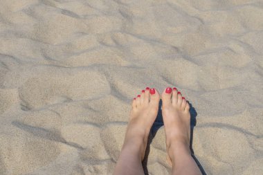Yaz mevsiminde kumda kırmızı tırnaklı kadın ayakları
