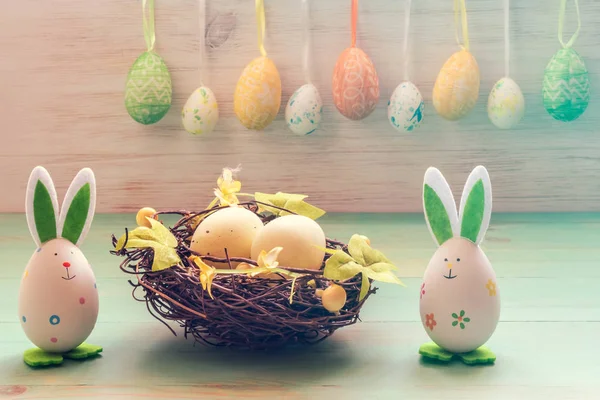 Jouets de lapins mignons, nid avec des œufs et rangée d'œufs de Pâques sur fond de bois vintage. Concept vacances de Pâques — Photo
