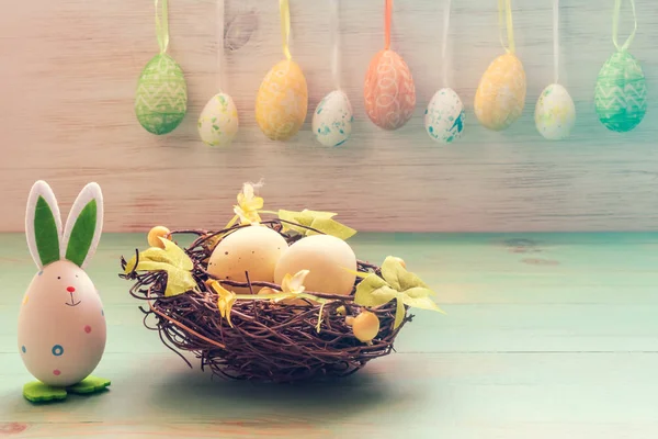 Nid de brindilles avec des œufs, joli lapin jouet et rangée d'œufs de Pâques sur fond de bois vintage. Décoration de Pâques vacances — Photo
