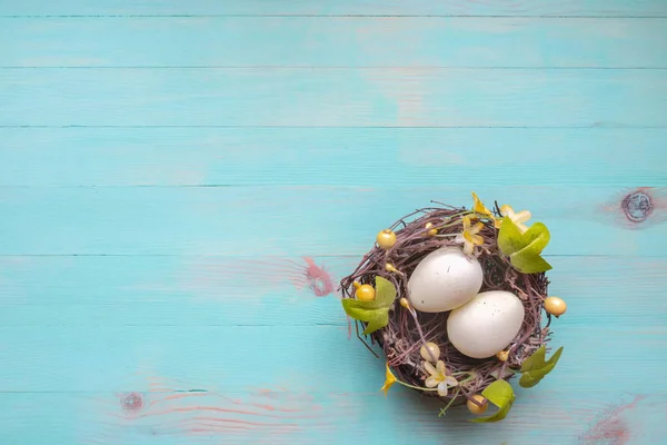 Œufs de Pâques dans le nid de brindilles sur fond de bois azur vintage — Photo