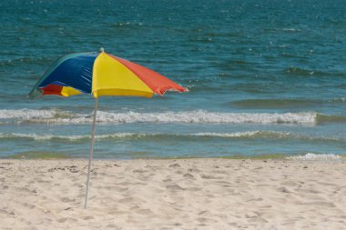 Colorful beach umbrella on tropical beach and sea with waves in background