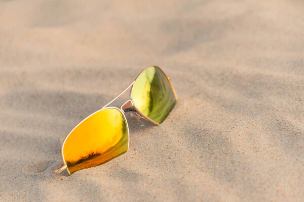 Sunglasses with dunes reflection in sand at beach in summertime vacation