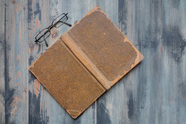 Vintage hoary arka plan üzerinde kapalı antik kitap ve gözlük Düz yatıyordu. Kopyalama alanı