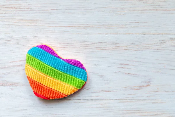 One rainbow heart-shaped pillow on wooden board. Mockup for LGBT. Valentine\'s day background.