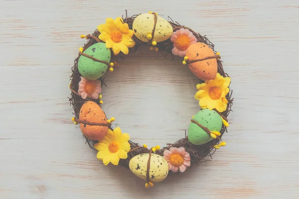 Oeufs de Pâques et couronne de fleurs sur fond de bois vintage — Photo